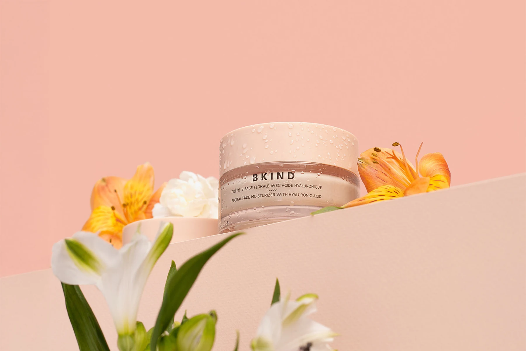 Crème visage florale BKIND, commanditaire principal de la soirée, sur un fond rose poudré avec des lys.